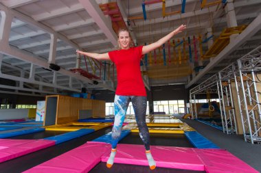 Fitness, eğlence, eğlence ve spor aktivite konsepti - Genç mutlu kadın kapalı bir trambolin üzerinde atlama