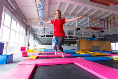 Fitness, eğlence, eğlence ve spor aktivite konsepti - Genç mutlu kadın kapalı bir trambolin üzerinde atlama
