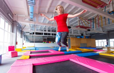 Fitness, eğlence, eğlence ve spor aktivite konsepti - Genç mutlu kadın kapalı bir trambolin üzerinde atlama