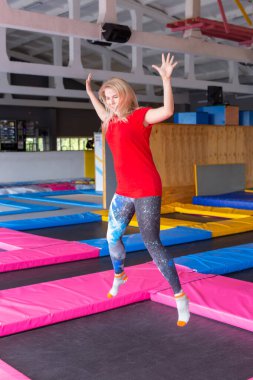 Fitness, eğlence, eğlence ve spor aktivite konsepti - Genç mutlu kadın kapalı bir trambolin üzerinde atlama