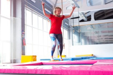 Fitness, eğlence, eğlence ve spor aktivite konsepti - Genç mutlu kadın kapalı bir trambolin üzerinde atlama