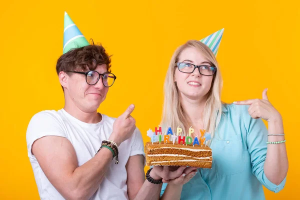 젊은 쾌활한 학생 매력적인 소녀와 케이크를 들고 종이 모자를 인사하는 좋은 사람. 생일과 기념일에 축 하의 개념 — 스톡 사진