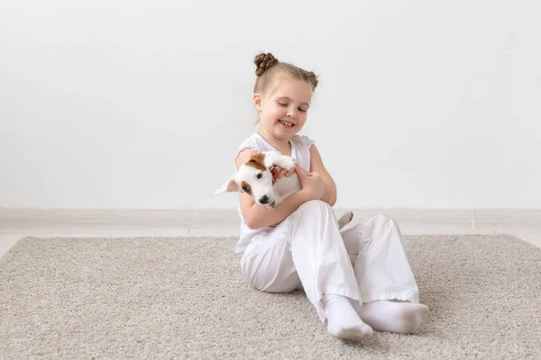 Mascotas, concepto de la infancia y los animales - Retrato de niña sentada en el suelo con el cachorro Jack Russell Terrier — Foto de Stock