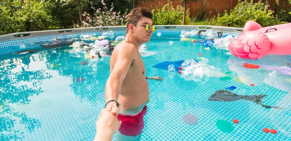 Ecologie, plastic afval, milieu nood en watervervuiling-Guy leiden in een zwembad met vuilnis — Stockfoto