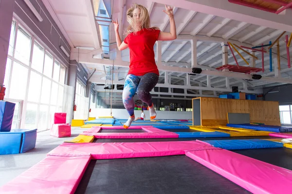 Fitness, diversão, lazer e esporte conceito de atividade - Jovem mulher feliz pulando em um trampolim dentro de casa — Fotografia de Stock