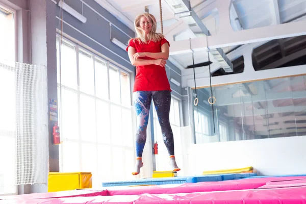 Fitness, diversión, ocio y deporte concepto de actividad - Mujer feliz joven saltando en un trampolín en el interior — Foto de Stock