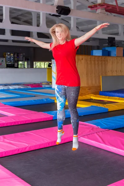 Koncepcja aktywności fizycznej, zabawy, wypoczynku i sportu-młoda szczęśliwa kobieta Skacząca na trampolinie w pomieszczeniu — Zdjęcie stockowe