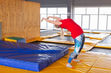 Spor salonundaki trambolinde spor yapan genç bir kadın.