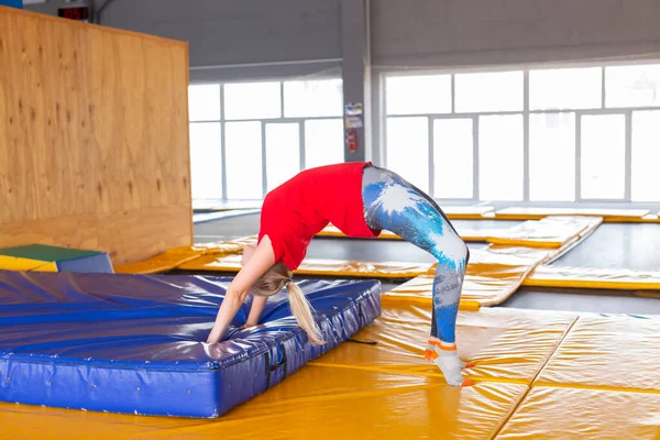 Mladá žena sportovec na trampolíně ve fitness parku a dělat cvičení uvnitř — Stock fotografie