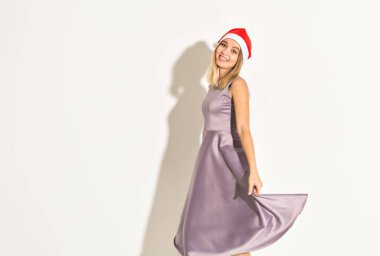Yeni yıl ve tatil konsepti Noel Baba şapkalı mutlu genç kadın dans ediyor ve beyaz arka planda gülüyor..