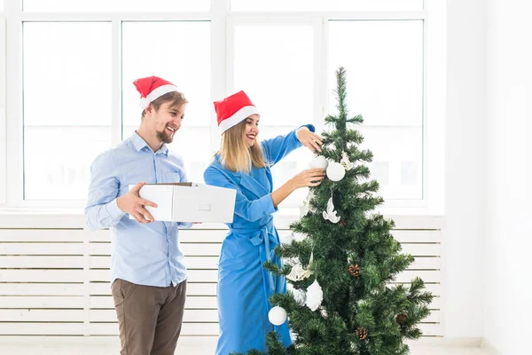 Holidays and festive concept - Young family couple decorating the christmas tree — ストック写真