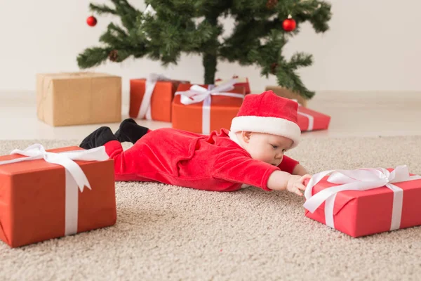 Linda niña con traje de Santa Claus arrastrándose por el suelo sobre el árbol de Navidad. Temporada de vacaciones . — Foto de Stock