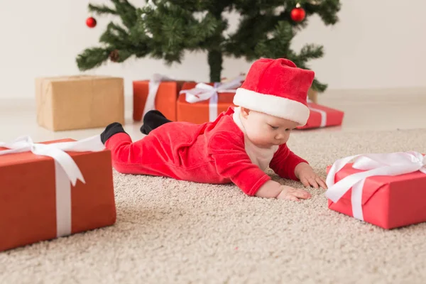 Carina la bambina che indossa la tuta di Babbo Natale strisciando sul pavimento sopra l'albero di Natale. Stagione delle vacanze . — Foto Stock