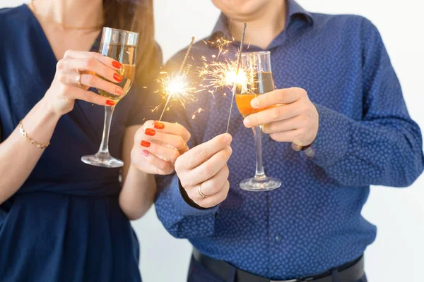 Close-up de homem e mulher comemorando a festa de Natal ou Ano Novo com luzes de Bengala e copos de champanhe . — Fotografia de Stock