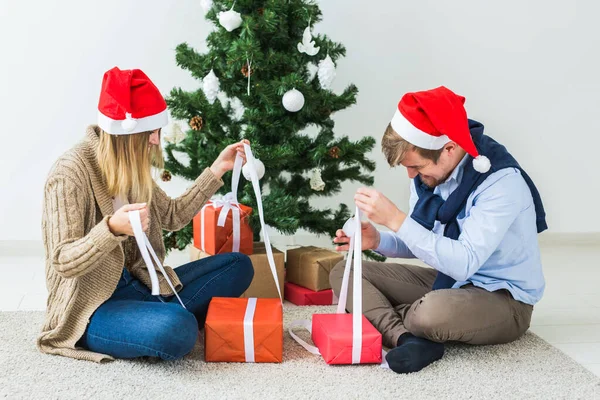 休日のコンセプト – 甘いカップルはクリスマスプレゼントを開き、リビングルームに座って — ストック写真