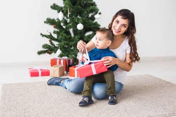 Navidad, padre soltero y el concepto de vacaciones - Lindo niño sosteniendo regalo de Navidad para su madre en el hogar . — Foto de Stock