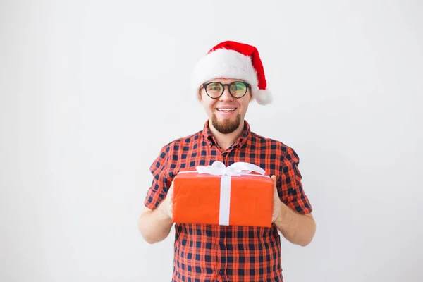 Concepto de Navidad y vacaciones - Hombre divertido en sombrero de santa celebración de un regalo sobre fondo blanco —  Fotos de Stock