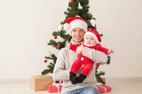 Vader met zijn babyjongen dragen van Santa hoeden we vieren kerst. — Stockfoto