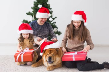 Evcil hayvan, tatil ve festival konsepti. Köpekli aile Noel ağacının yanında duruyor..