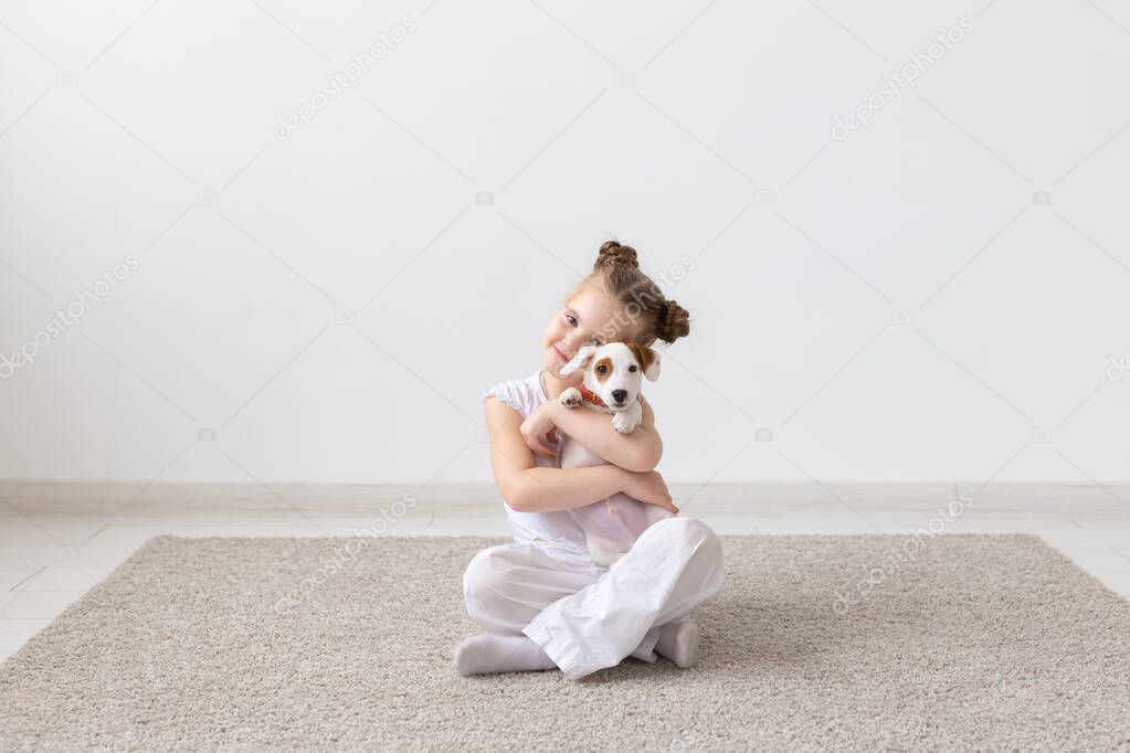 Dogs, children and pets concept - little child girl sitting on the floor with cute puppy