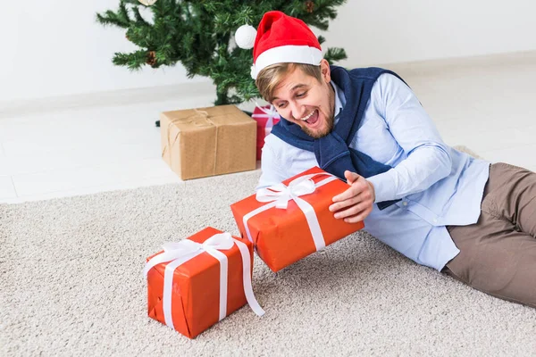 クリスマスと休日のコンセプト-サンタのハッピーマン帽子リビングルームで自宅で贈り物を開く — ストック写真