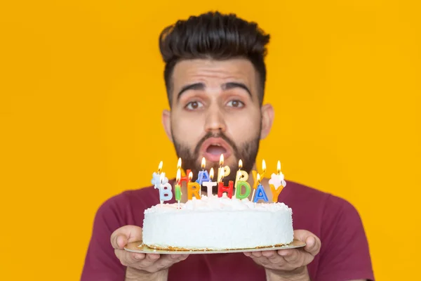 Young male hipster with a beard holding a cake with the inscription happy birthday congratulations on the anniversary and the holiday. Concept of promotions and discounts.