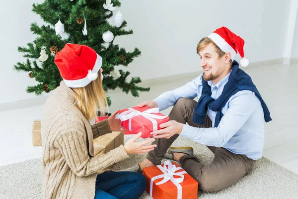 休日のコンセプト – 甘いカップルはクリスマスプレゼントを開き、リビングルームに座って — ストック写真