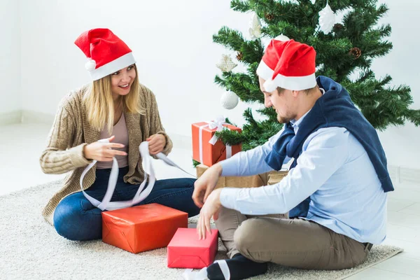 休日のコンセプト – 甘いカップルはクリスマスプレゼントを開き、リビングルームに座って — ストック写真