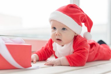 Güzel küçük bebek Noel 'i kutluyor. Yeni yıl tatili. Noel kostümü içindeki bebek ve Noel Baba şapkası