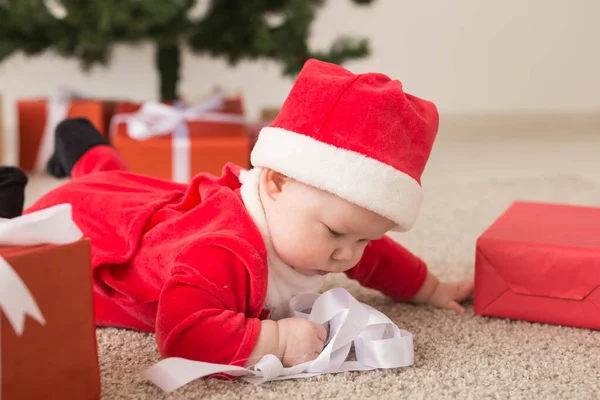 Bellissimo bambino festeggia il Natale. Vacanze di Capodanno. Bambino in costume natalizio e in cappello da Babbo Natale e confezione regalo — Foto Stock