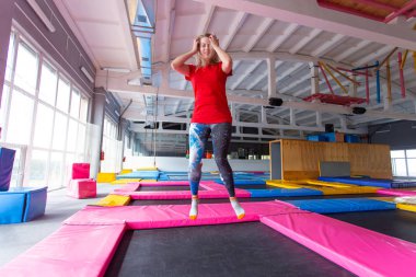 Fitness, eğlence, eğlence ve spor aktivite konsepti - Genç mutlu kadın kapalı bir trambolin üzerinde atlama