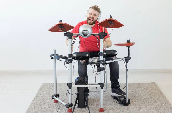 Mensen, muziek en hobby concept-man met witte koptelefoon het spelen van de drums instellen over lichte achtergrond — Stockfoto