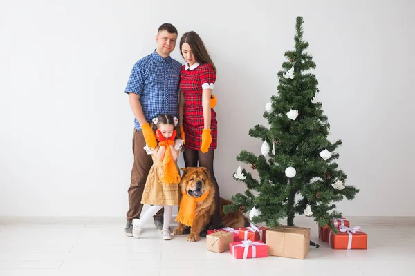 Mascotas, vacaciones y concepto festivo - Familia con perro están de pie cerca del árbol de Navidad . — Foto de Stock