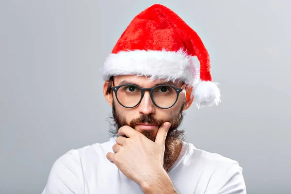 Concepto de vacaciones y personas - Retrato de un hombre guapo y brutal en sombrero de Navidad. Sobre fondo gris . — Foto de Stock