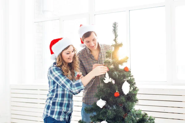 家族、 x-mas 、冬の休日と人々のコンセプト-家庭でクリスマスツリーを飾る幸せな若いカップル — ストック写真