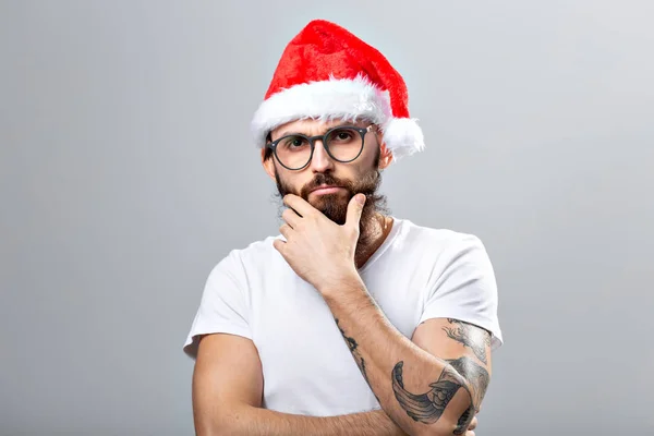 Concepto de vacaciones y personas - Retrato de un hombre guapo y brutal en sombrero de Navidad. Sobre fondo gris . — Foto de Stock