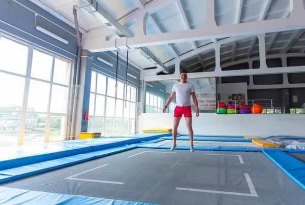 Koncepcja aktywności fizycznej, zabawy, wypoczynku i sportu-przystojny szczęśliwy człowiek skoki na trampolinie w pomieszczeniu — Zdjęcie stockowe