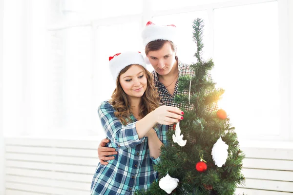Família, x-mas, férias de inverno e conceito de pessoas - feliz jovem casal decoração árvore de Natal em casa — Fotografia de Stock