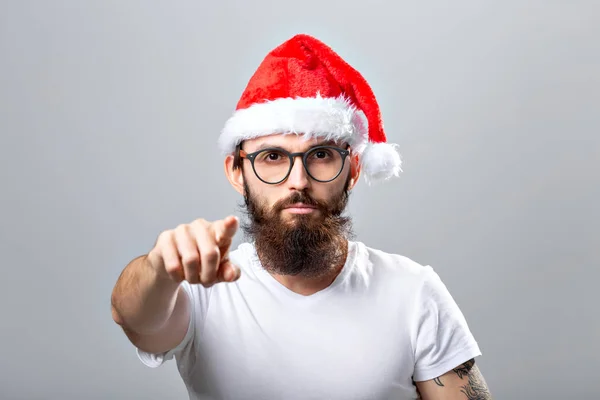 Holidays and people concept - Portret van een knappe brutale man met kerstmuts. Over grijze achtergrond. — Stockfoto