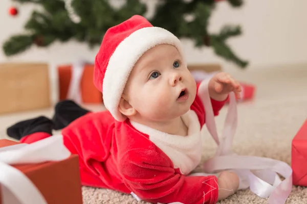 Piękne maleństwo świętuje święta. Noworoczne wakacje. Dziecko w stroju świątecznym i w Santa kapelusz i pudełko prezentów — Zdjęcie stockowe