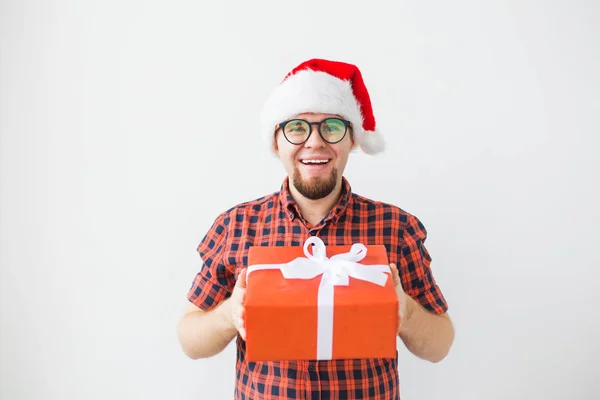 Concepto de Navidad y vacaciones - Hombre divertido en sombrero de santa celebración de un regalo sobre fondo blanco —  Fotos de Stock