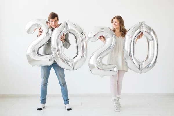 休日、お祝いやパーティーのコンセプト-幸せな愛情のカップルのキスと白い背景に銀2020風船を保持しています。新年のお祝い — ストック写真