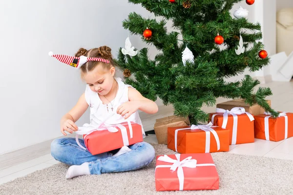 Kinder öffnen Weihnachtsgeschenke. Kind unterm Weihnachtsbaum mit Geschenkschachteln. — Stockfoto