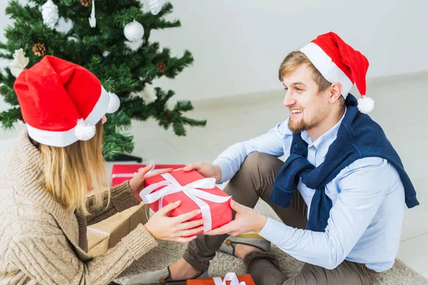 Holidays, family and festive concept - Couple with Christmas gifts at home