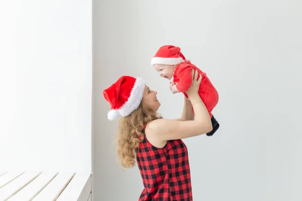 Familia, infancia y concepto de Navidad - Madre joven sosteniendo al bebé en traje de santa interior — Foto de Stock