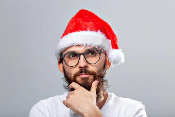 Concepto de vacaciones y personas - Retrato de un hombre guapo y brutal en sombrero de Navidad. Sobre fondo gris . —  Fotos de Stock
