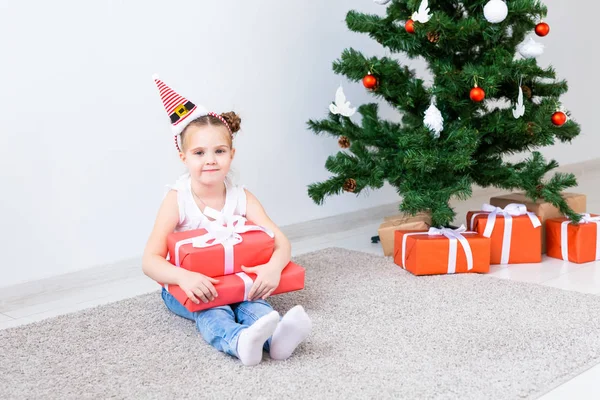 Regali di Natale per l'apertura dei bambini. Bambino sotto l'albero di Natale con scatole regalo . — Foto Stock