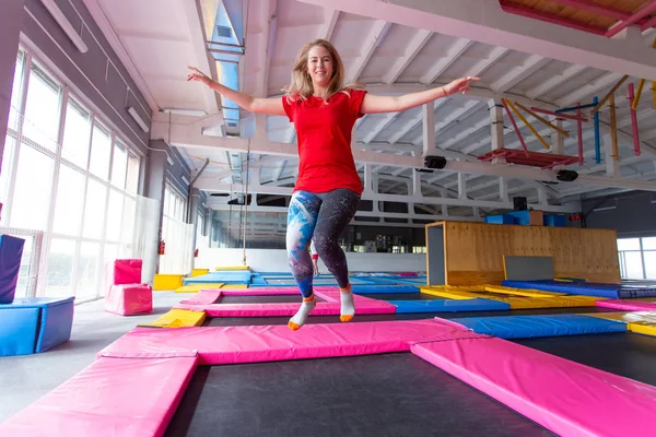 Fitness, eğlence, eğlence ve spor aktivite konsepti - Genç mutlu kadın kapalı bir trambolin üzerinde atlama