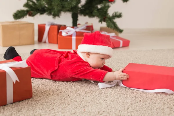 Hermoso bebé celebra la Navidad. Vacaciones de Año Nuevo. Bebé en un disfraz de Navidad y en sombrero de santa y caja de regalo — Foto de Stock