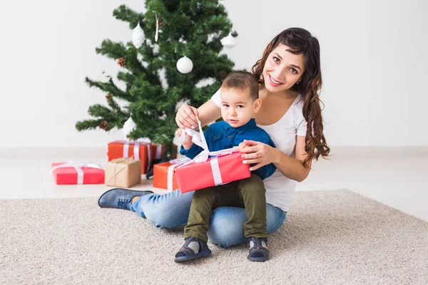 Boże Narodzenie, samotny rodzic i koncepcja święta - Cute little boy gospodarstwa Boże Narodzenie prezent dla matki w domu. — Zdjęcie stockowe